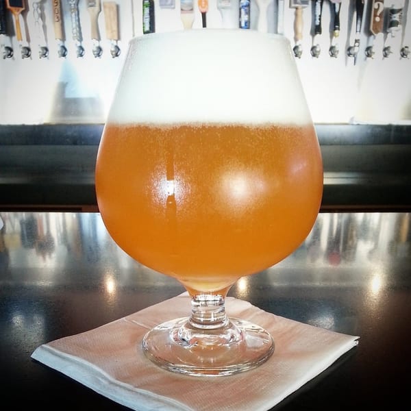 A foamy glass of 38 Degrees Ale House & Grill's craft beer sits on a bar.